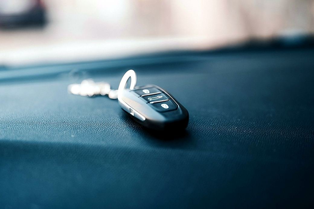 A car key fob with remote buttons lying on a dashboard