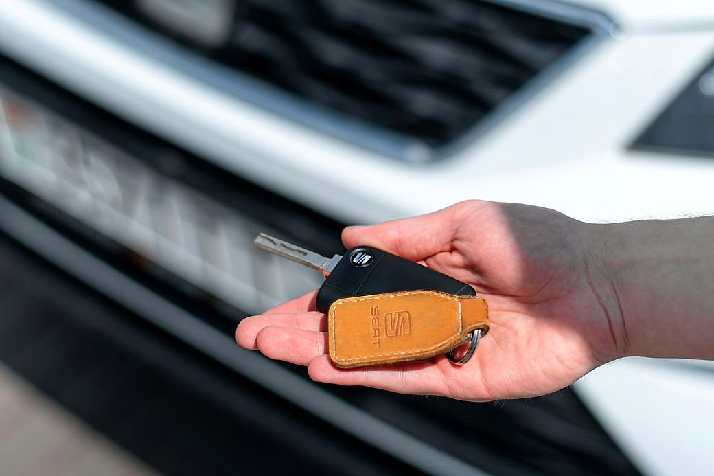 The only car key held in a hand in front of a car