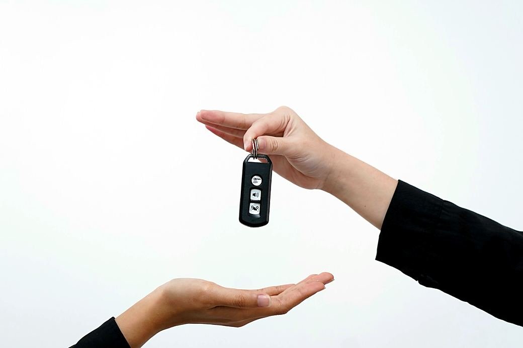 A car key passed from one hand to another, for a second driver
